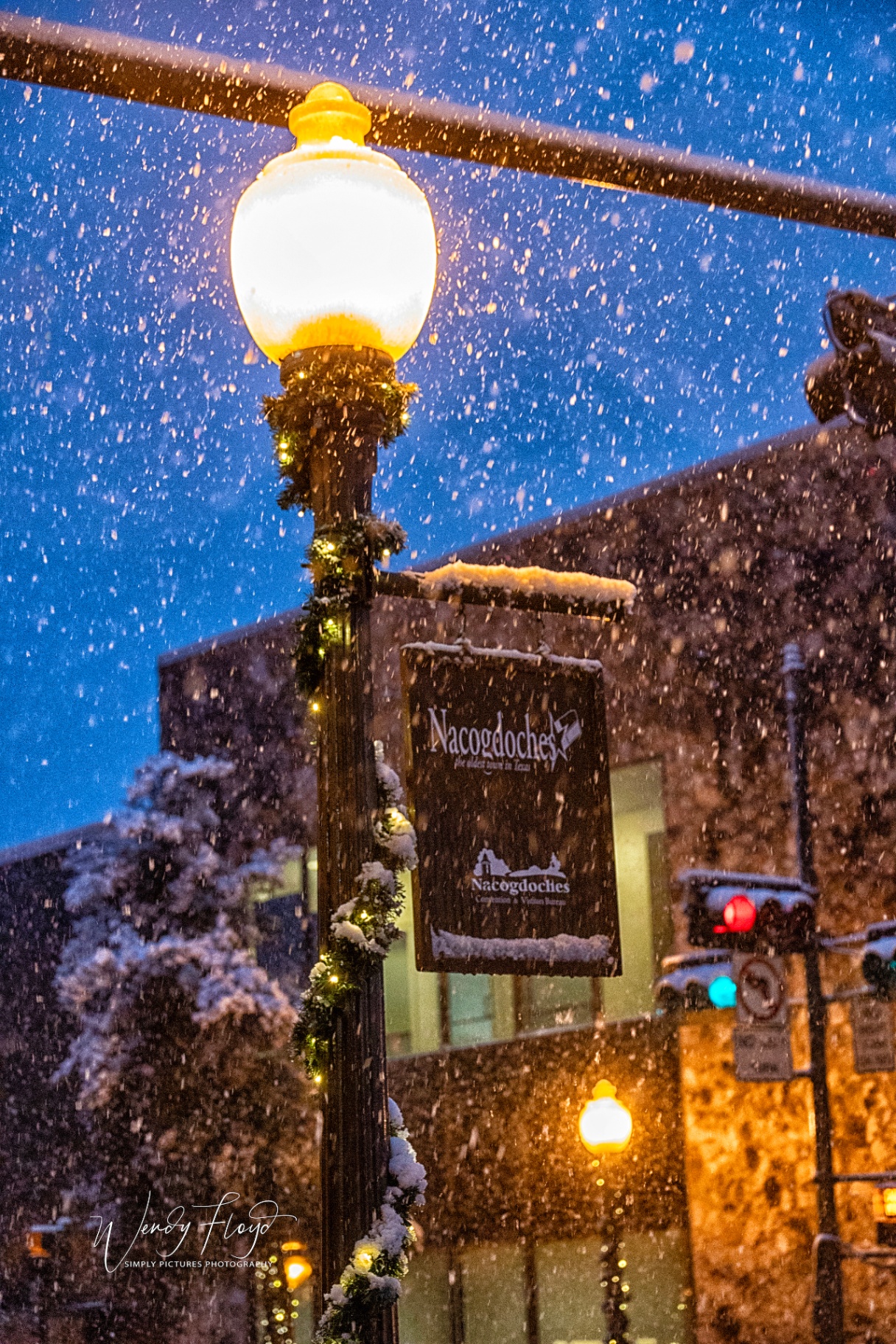 Snow falling on a decorated downtown Nacogdoches lamppost at dusk